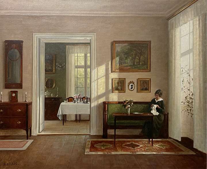 An interior with a woman sitting on a sofa